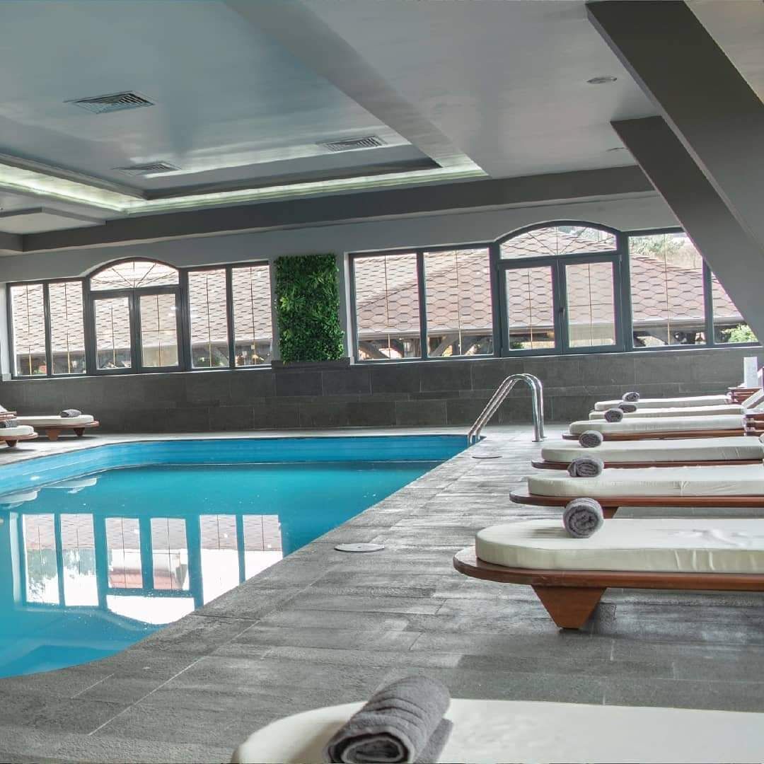 A swimming pool with lounge chairs and a water slide.