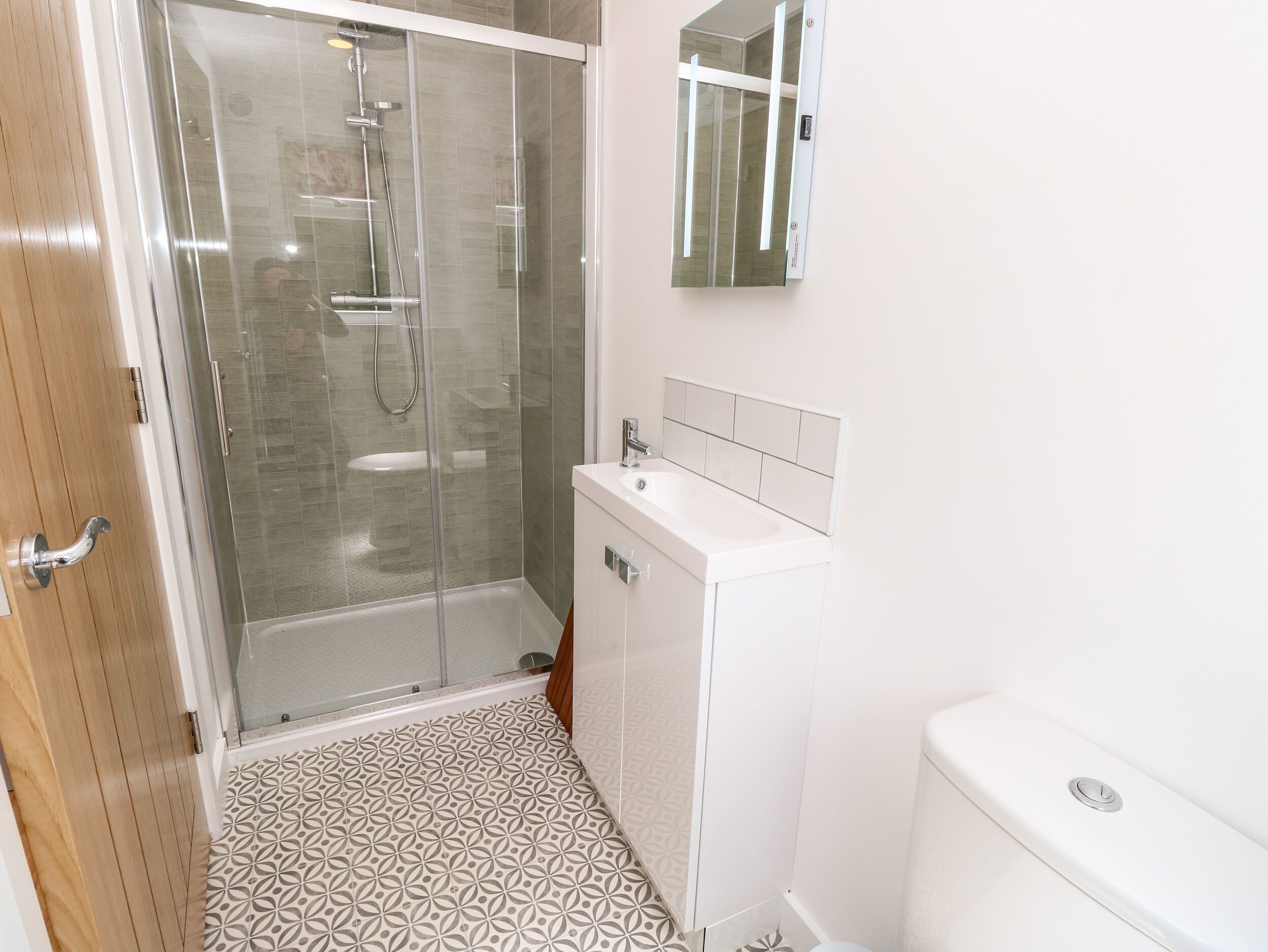 Une salle de bain avec une douche à parois de verre, un lavabo blanc et des toilettes.