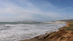 A coastal landscape with cliffs and a wooden walkway leading to the beach. - Cava (Ryde)