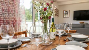 A dining table set with plates, glasses, and a vase of flowers. - Cava (Ryde)