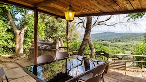 Un espace extérieur abrité, avec une table et des chaises, offrant une vue sur un paysage pittoresque.