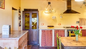 Une cuisine rustique avec des poutres en bois, un poêle et un panneau indiquant qu’il s’agit d’un café proposant également des visites guidées.