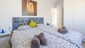 A hotel room with a bed, a painting on the wall, and a door.