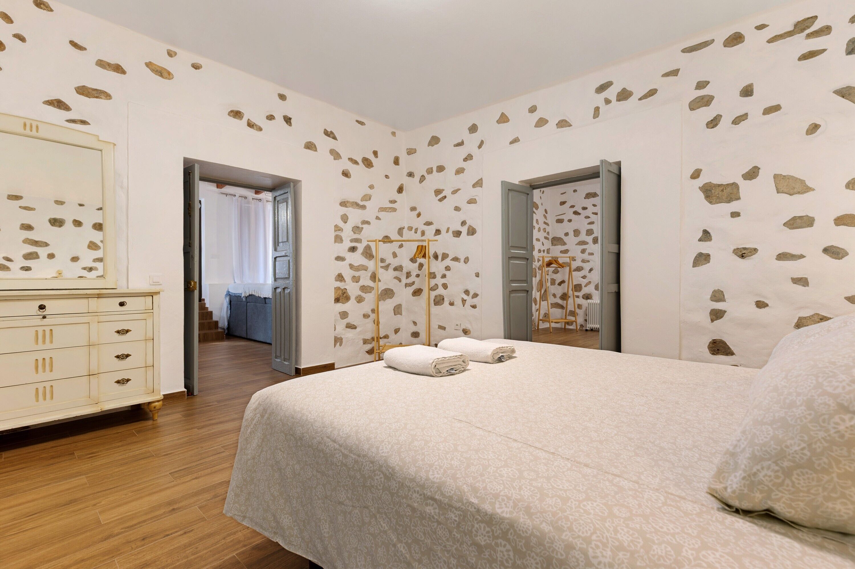 Een slaapkamer met een bed, een dressoir en een spiegel.