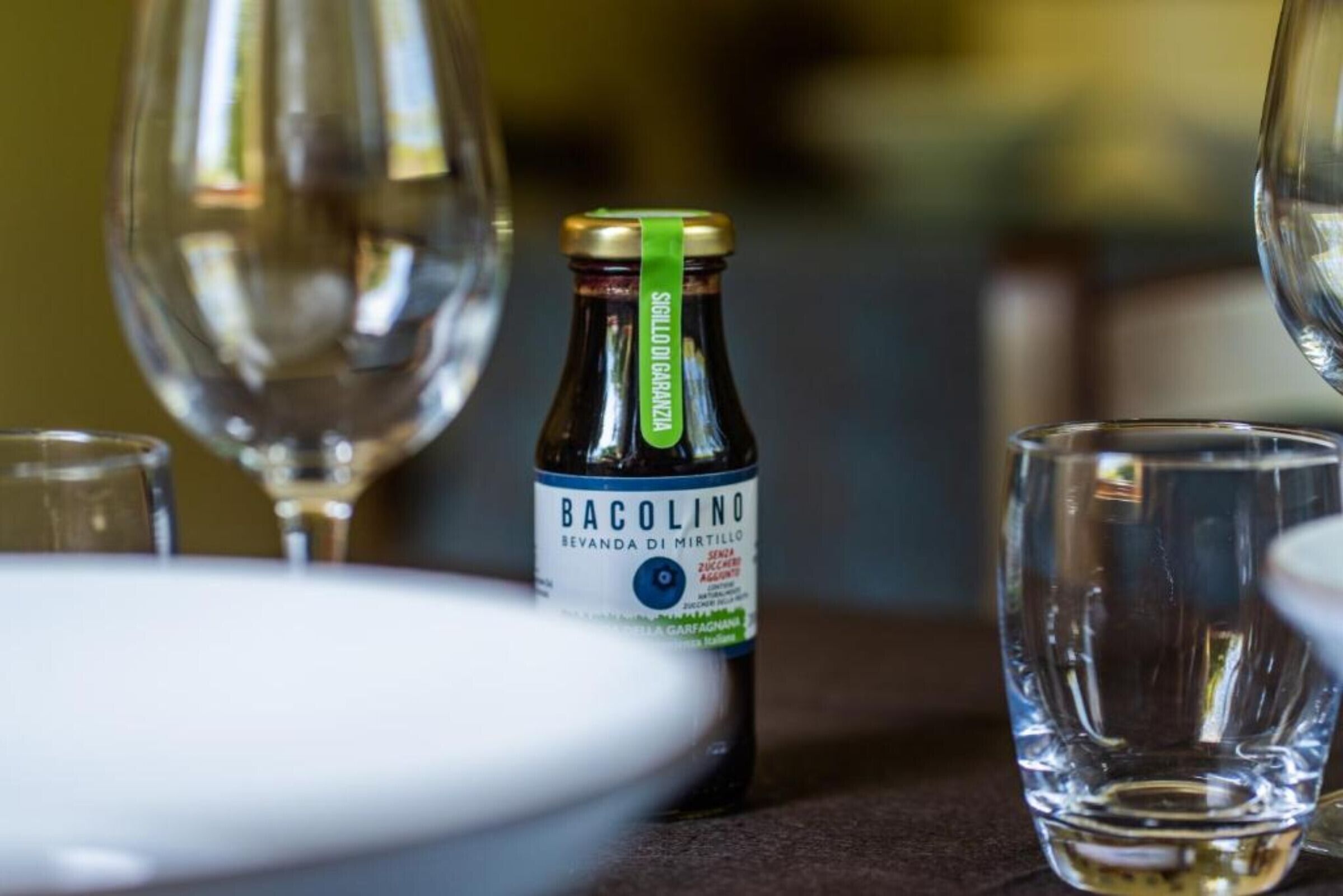 A bottle of Bacolino wine with a label, placed on a table with a glass and a plate.