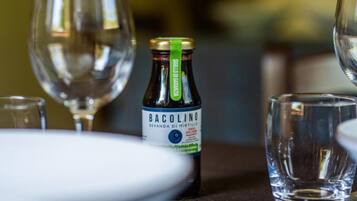 A bottle of Bacolino wine with a label, placed on a table with a glass and a plate.