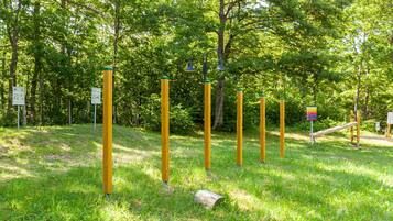 Ein Park mit gelben Pfosten, einer Holzkonstruktion und grünen Bäumen.