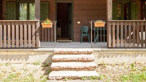 A wooden cabin with a porch, stone steps, and two chairs. - Chalet Scoiattolo with Mountain Views and Terrace (Capanne)