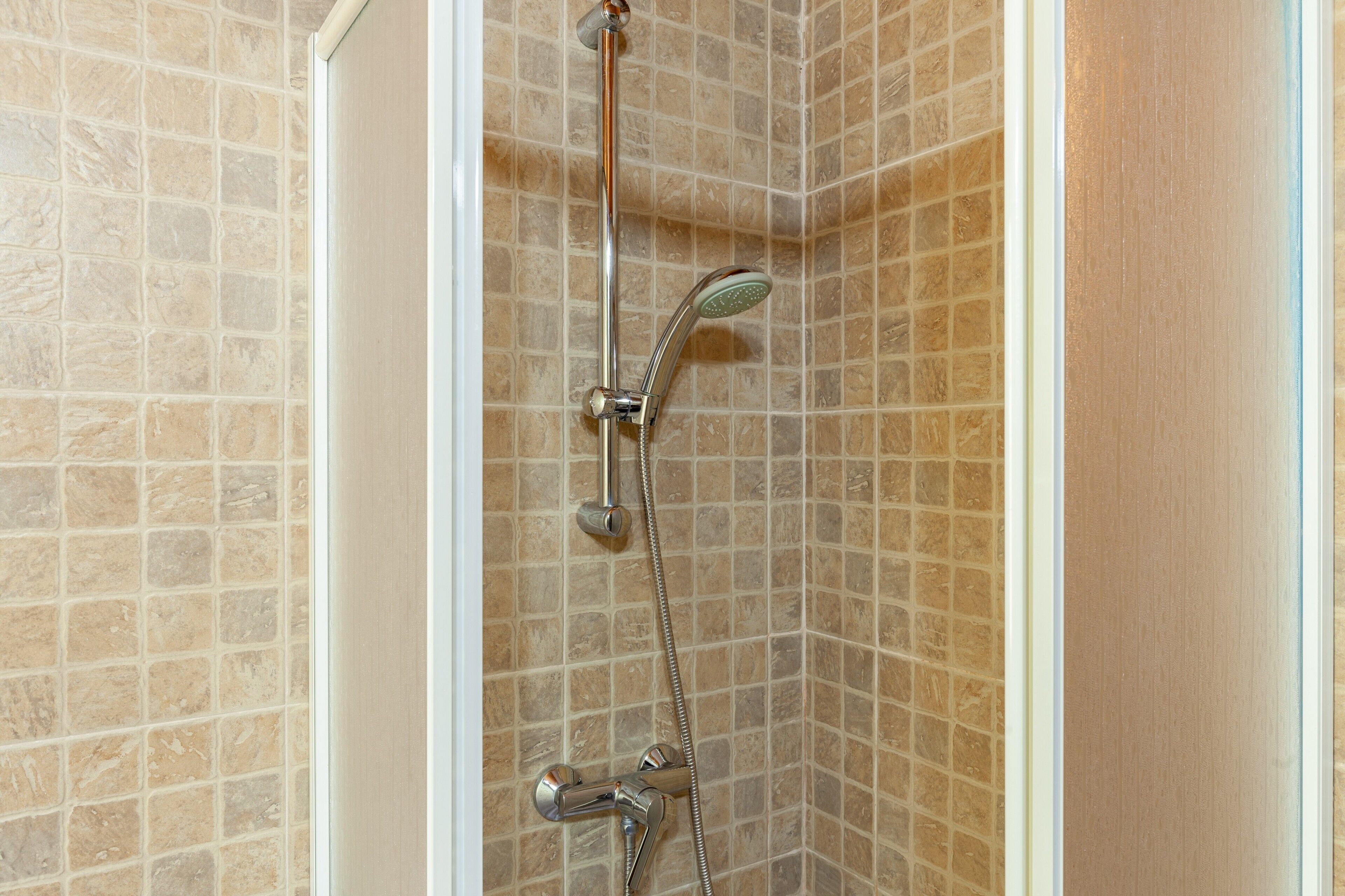 A shower with a handheld showerhead and a wall-mounted faucet.