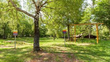 Ein Park mit einer Holz-Schaukel, einem Baum und Wegweisern.