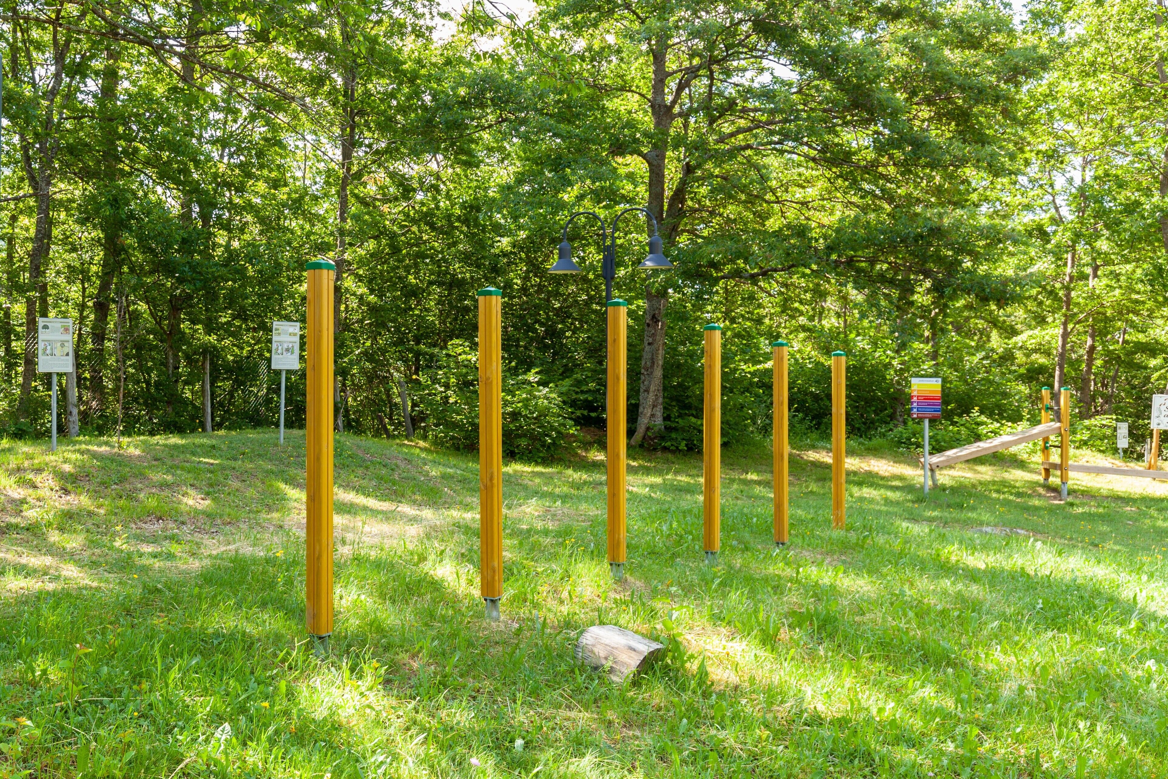 Un parc avec des poteaux jaunes, une structure en bois et des arbres verts.