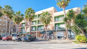 Un hotel de varios pisos con balcones, palmeras y zonas de estar al aire libre.