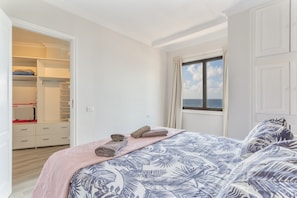 A bedroom with a bed, a closet, and a window with a view.