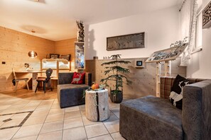 Une pièce chaleureuse avec un décor intérieur en bois, un bureau avec une chaise, un canapé et une petite table agrémentée d’un objet décoratif.