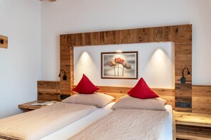 A double bed with two red pillows, a wooden headboard, a framed artwork above the bed, and bedside tables with lamps. - Holiday Apartment 'Hatzes Panorama' with Mountain Views, Balconies & Wi-Fi (Lajen)
