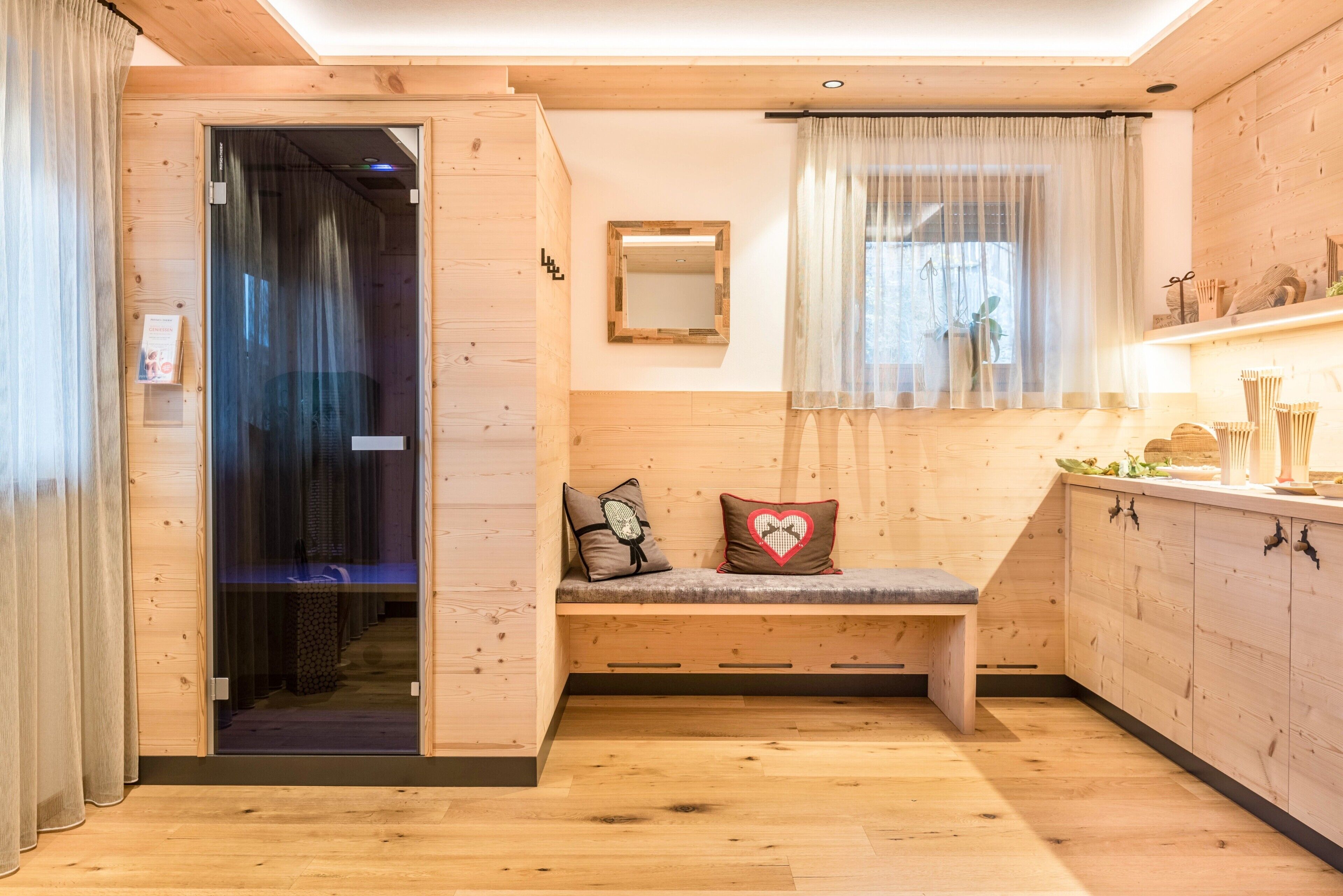 Un intérieur en bois avec un banc, un miroir et une fenêtre ornée de rideaux légers.