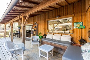 Une terrasse en bois avec des meubles en osier, un canapé et un panneau indiquant un lieu.