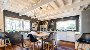Uma cozinha moderna com mesa de madeira, banquetas e uma janela grande.