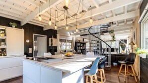 Uma cozinha moderna com ilha central, banquetas e luminárias pendentes.