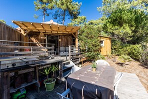 A wooden deck with outdoor seating, a grill, and a small wooden structure. - 'Studio 500m from Carcans Beach' with Garden & Wi-Fi (Carcans)