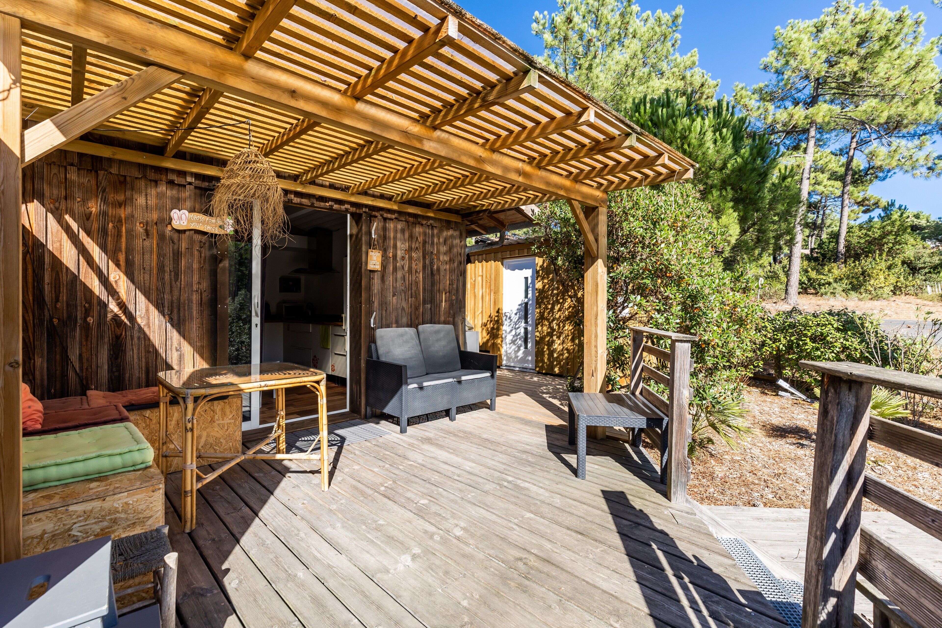A wooden deck with outdoor furniture, a pergola, and a view of trees.