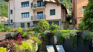 A rooftop garden with plants, a seating area, and a building with balconies.