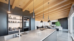 A modern kitchen with a central island, built-in appliances, and pendant lighting.
