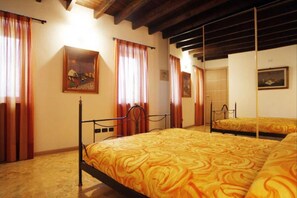 Une chambre avec deux lits, des poutres en bois au plafond et un tableau au mur.