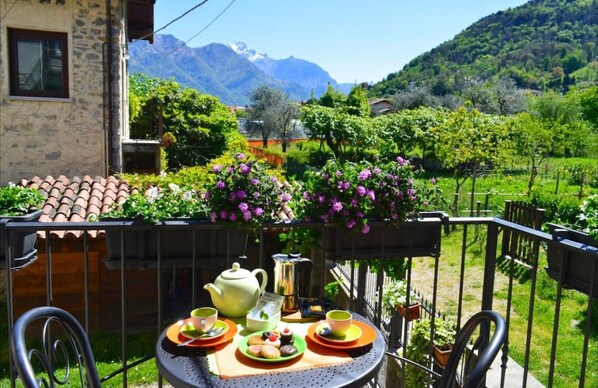 Un balcon avec une table dressée pour le thé, entouré d’une végétation luxuriante et avec une chaîne de montagnes en toile de fond.