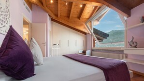 Een slaapkamer met een bed, een raam, een radiator en uitzicht op buiten.