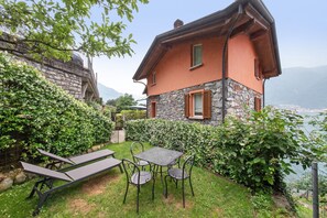 Uma casa com fachada de pedra, varanda e vista para um lago.