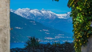 A stone wall, a grassy area, and a mountain view through an archway.