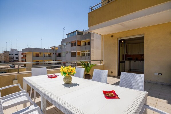 A balcony with a table, chairs, and a potted plant.