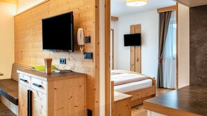 Ein modernes Zimmer mit Holzwand, einem Bett, einem Fernseher, einem Schreibtisch und einem Vorhangfenster.