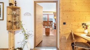 Ein Holzinterieur mit einer Tür, die in einen Essbereich führt, einem Regal mit Dekorationen und einer Vase mit Blumen.