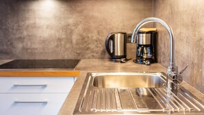 Eine moderne Küche mit Spüle aus Edelstahl, einer Kaffeemaschine und einem Wasserkocher auf der Arbeitsfläche.