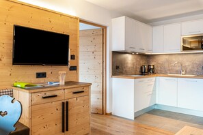 Une cuisine moderne avec des meubles en bois, un téléviseur encastré et une machine à café.