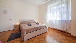 A bedroom with a bed, bedside table, and a window with curtains. - Residence Hubertus Apartment 5 with  Balcony & Wi-Fi (Meran)