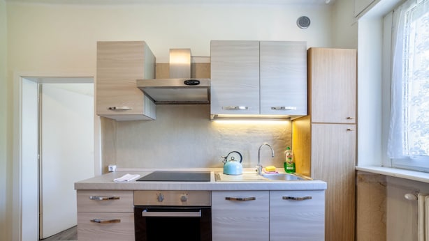 A compact kitchen with a built-in oven, a sink, and wooden cabinets. - Residence Hubertus Apartment 6 with Balcony & Wi-Fi (Meran)