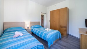 A bedroom with two beds, a wardrobe, a bedside table, and a TV. - Residence Hubertus Apartment 6 with Balcony & Wi-Fi (Meran)