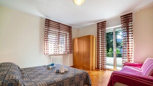 A bedroom with a bed, a sofa, a wardrobe, and a window with curtains. - Residence Hubertus Apartment 2 with Balcony & Wi-Fi (Meran)