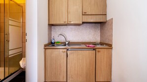 A compact kitchen with wooden cabinets, a stainless steel sink, and a tiled backsplash. - Residence Hubertus Apartment 2 with Balcony & Wi-Fi (Meran)