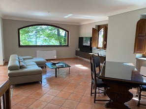 Una sala de estar con sofá, mesa de centro, televisor y un comedor con mesa y sillas.