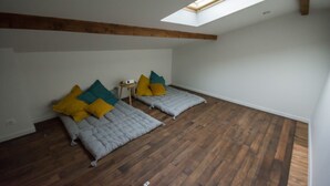 A room with a sloped ceiling, wooden beams, a skylight, two beds with pillows, and a small table. - Large 220m2 house, near town center with garden (Limoges)