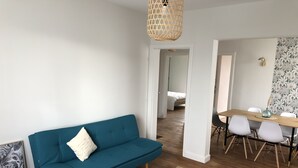 A modern living room with a teal sofa, a round marble coffee table, and a dining area with a wooden table and white chairs. - Large 220m2 house, near town center with garden (Limoges)