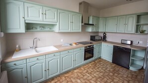 A kitchen with light green cabinets, a wooden countertop, a sink, a microwave, an oven, and a dishwasher. - Large 220m2 house, near town center with garden (Limoges)
