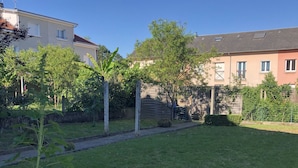 A residential area with a grassy lawn, trees, and a building with multiple windows and a sloped roof. - Large 220m2 house, near town center with garden (Limoges)