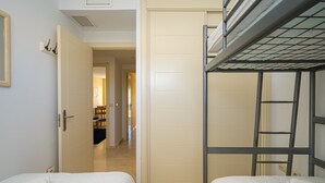 Een kamer met twee bedden, een kledingkast en een deur naar een andere kamer.