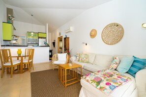 A living room with a sofa, a coffee table, and a dining area with chairs and a table.