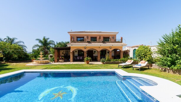 Una casa grande con piscina, fuente y un jardín bien cuidado.